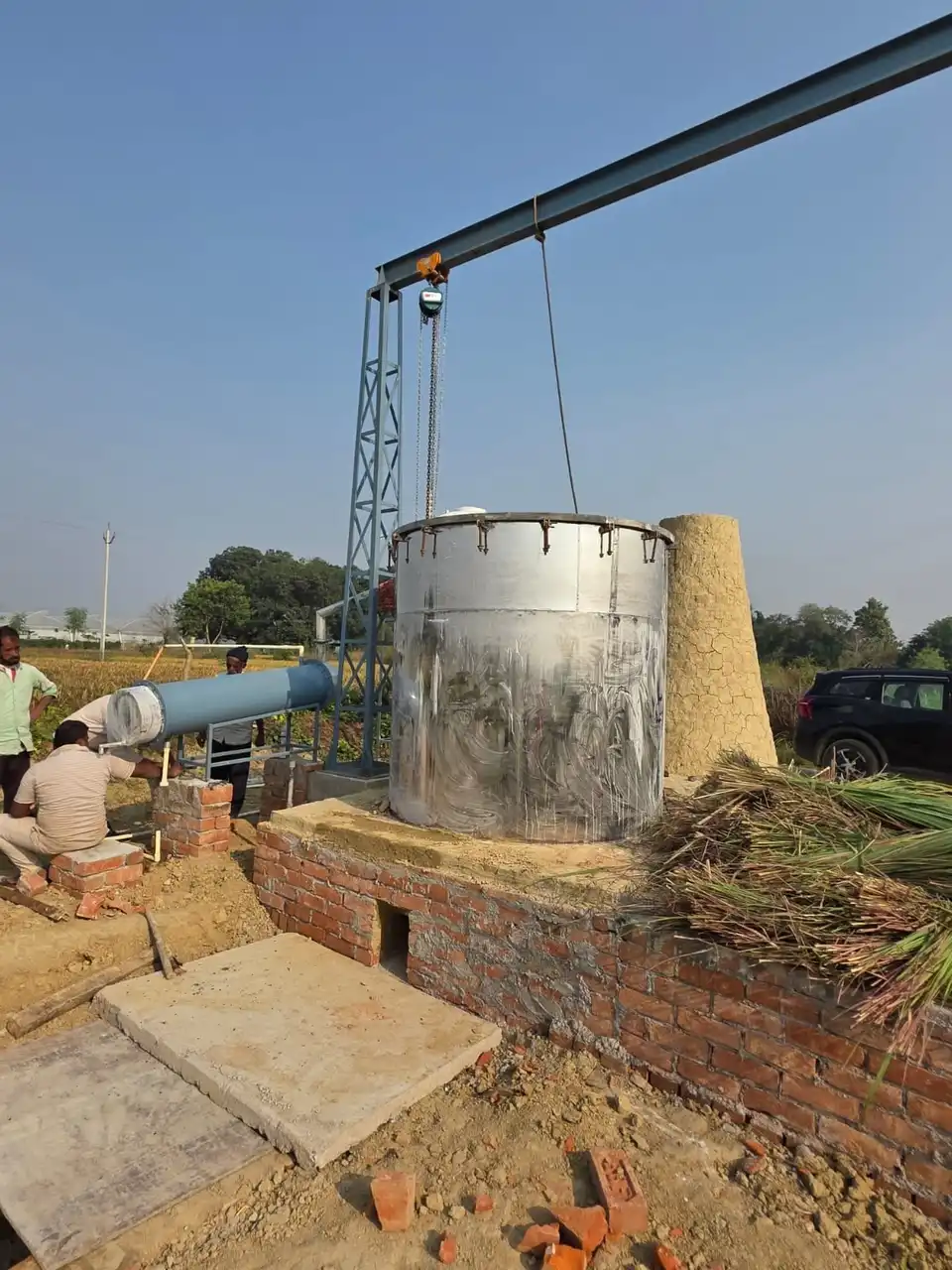 The farm's steel distillation tank beside bundles of cut lemongrass.